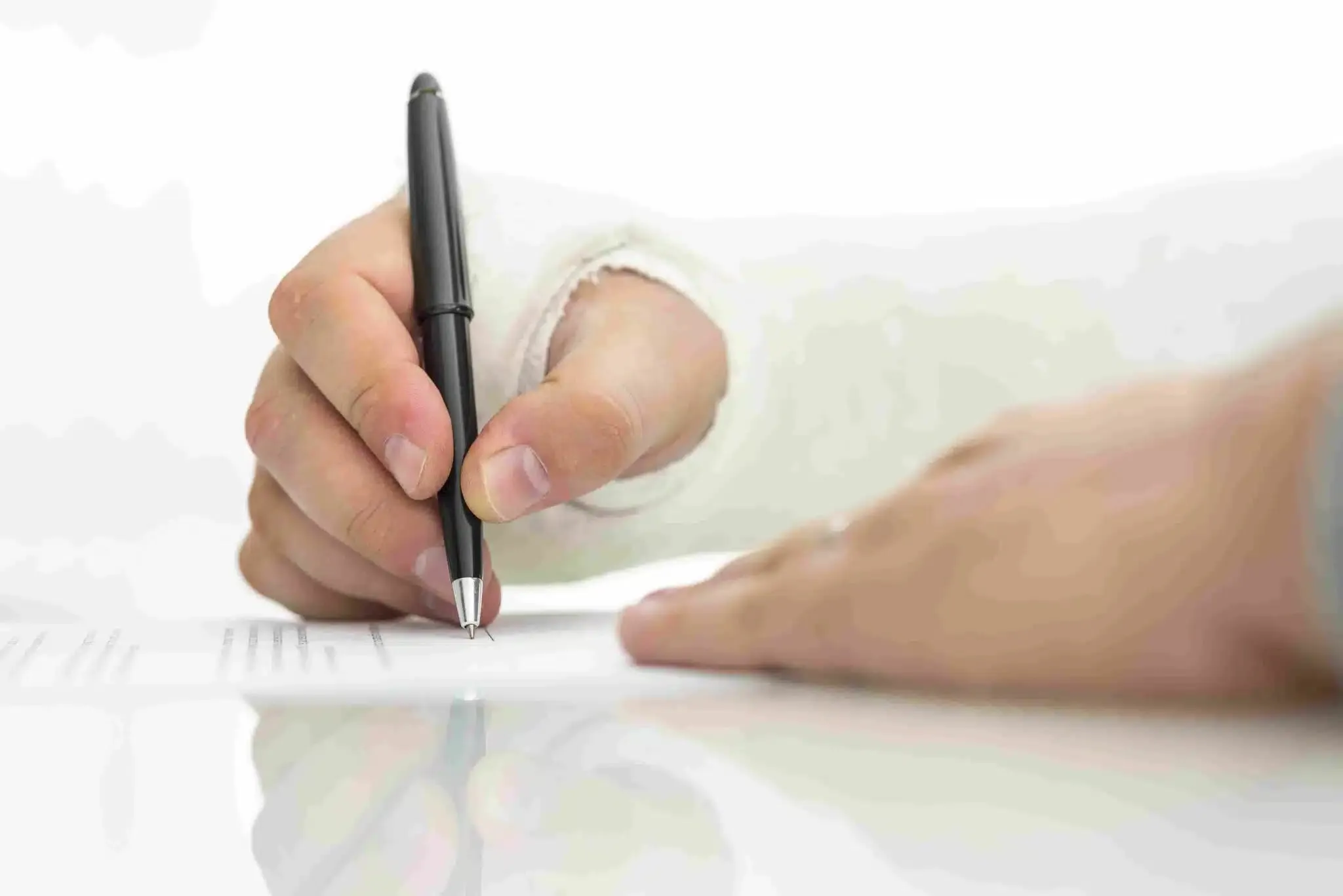 Hand signing a workers’ compensation or tax-related document on a desk